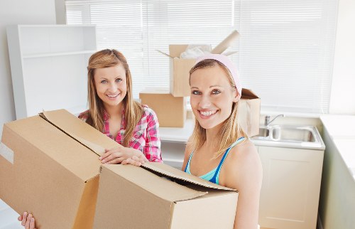 Professional movers carrying furniture through a narrow staircase